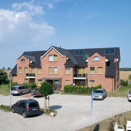 a large brick building with cars parked in a parking lot at Aparthotel Museumshof in Fehmarn