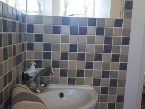 baño con lavabo y azulejos azules y grises en Golfbeach Luxury self catering apartment, en Ciudad del Cabo