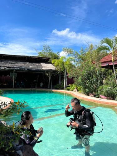 a man taking a picture of a woman in front of a swimming pool at AoJing Diving Resort澳鲸潜水温泉店 in Dauin