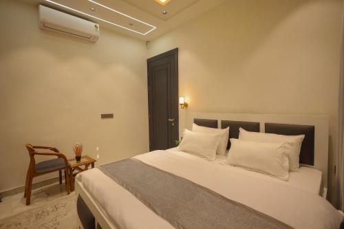 a bedroom with a bed with white pillows and a chair at Narayana Homes in Mathura