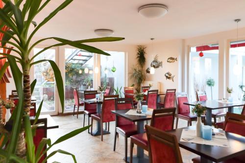 ein Restaurant mit Tischen und Stühlen und einer Topfpflanze in der Unterkunft Aparthotel Leuchtfeuer Rügen in Glowe