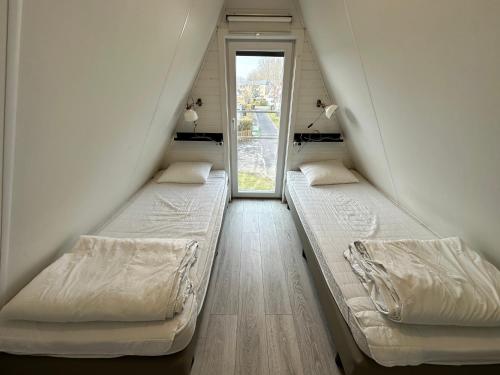 two bunk beds in a room with a window at Gezellige chalet in Nieuwpoort - Opkuis inbegrepen in de prijs in Oostduinkerke