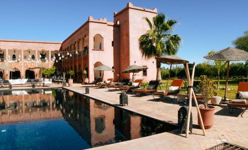 a resort with a swimming pool with chairs and umbrellas at Kasbah Caracalla in Aghmat