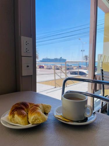a cup of coffee and a croissant on a table at Costanera Hotel in Puerto Madryn