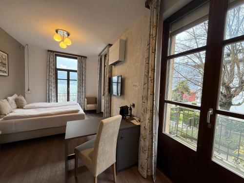 a bedroom with a bed and a desk and windows at Arbostora Charme Hotel in Morcote