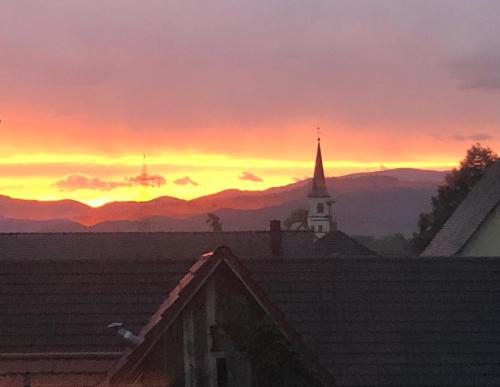 a sunset over a church with a steeple and a building at Kulturvogtei Freiburg-Tiengen in Freiburg im Breisgau