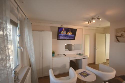 bagno con 2 sedie bianche e TV a parete di Ferienwohnung Spitz a Dornum