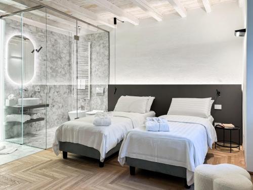 a bedroom with two beds and a glass shower at Villa Rêverie - Boutique Hotel in Bellano