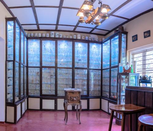 a room with tall windows and a table and a chair at Monticello Bungalow in Kotmale