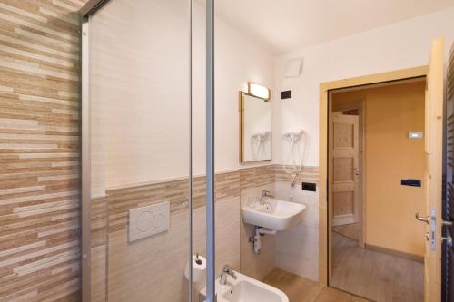 Un baño con lavabo y ducha de cristal. en Appartamento Legnameir Bait da Rez, en Livigno