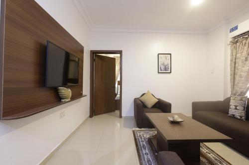 a living room with a couch and a tv on a wall at Peace Luxury Hotel and Apartment in Jahi