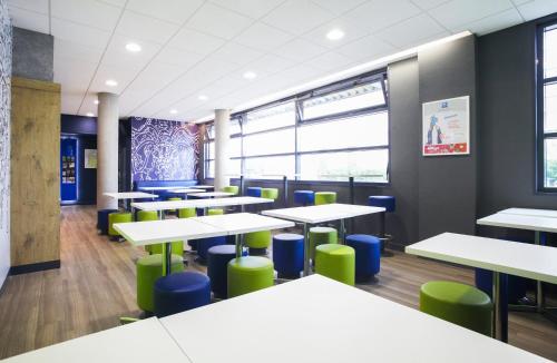 an empty classroom with tables and green chairs at Hotel Ibis Budget Nancy Centre in Nancy