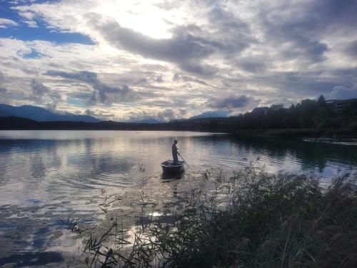 a man is rowing a boat on a lake at Haus Seebrise in Faak am See
