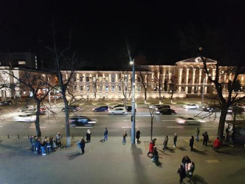 a group of people walking around a street at night at Ultracentral Apartment at Stefan Cel Mare Street in Chişinău
