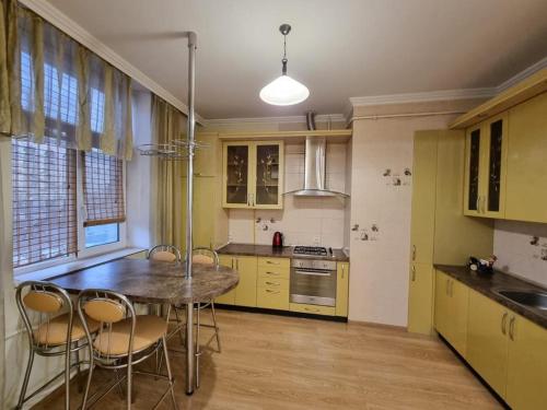 a kitchen with yellow cabinets and a table and chairs at Ultracentral Apartment at Stefan Cel Mare Street in Chişinău