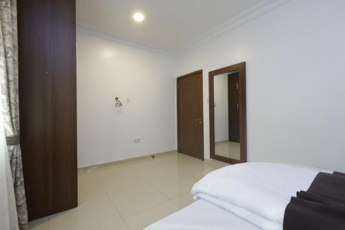 a white bedroom with a bed and a mirror at Peace Luxury Hotel and Apartment in Jahi