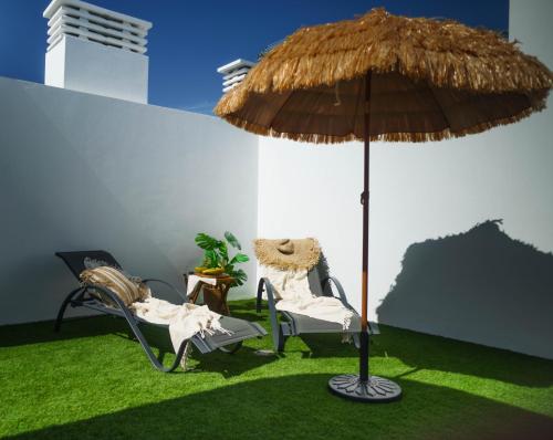 two chairs and an umbrella on the grass at Golden Suite Plaza in Corralejo