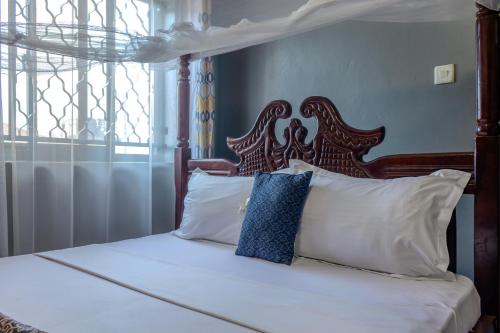 a bed with a wooden headboard and white pillows at Simba The lion Apartment Mawanda Road in Kampala