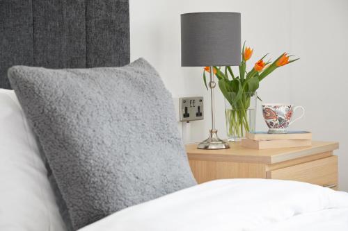 a bed with a pillow and a vase of flowers on a night stand at Luccombe Manor Country House Hotel in Shanklin