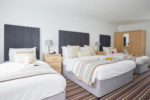 a bedroom with two beds with white sheets at Luccombe Manor Country House Hotel in Shanklin
