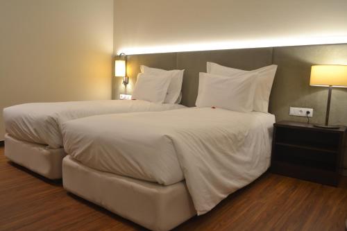 a bedroom with two beds with white sheets and pillows at Hotel Premium Porto Maia in Maia