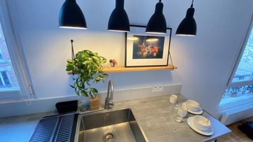 - une cuisine avec un évier et des lampes suspendues noires dans l'établissement A 5 minutes de la place de la nation, Studio, Paris, Rive Gauche, à Paris