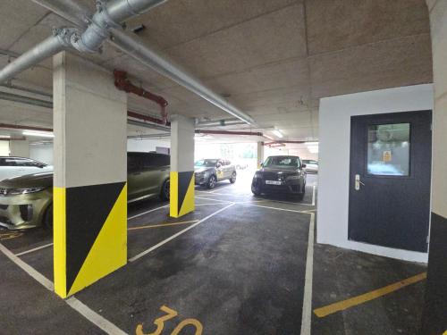 a parking garage with cars parked in it at Snuggle Inn Serviced Apartments, Great choice for large groups, Contractors, Business Executives and Family Vacations in the stunning valley of Surrey Hills, secure Private Parking, Offering Easy Train Access to London, Gatwick airport, M25 in Warlingham