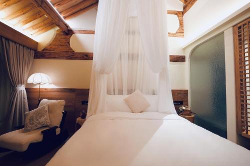 una camera da letto con un letto bianco con baldacchino di Leisure Courtyard Seascape Designer Hotel a Dali