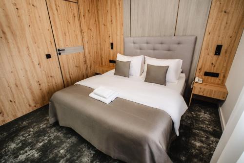 a large white bed in a room with wooden walls at Hotel Tomas in Šiauliai