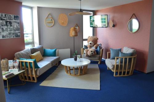 a living room with a couch and a teddy bear at BRIT HOTEL Caen Hérouville in Hérouville-Saint-Clair