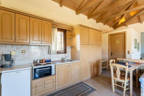 a kitchen with wooden cabinets and a sink and a table at Pleiades Studios All Season Gems - Korinthos Stone Retreats in Kalianoi