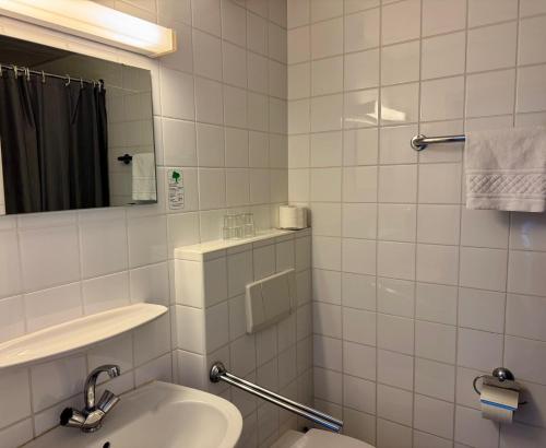 a white tiled bathroom with a sink and a mirror at Gästehaus Haßloch/Pfalz in Haßloch