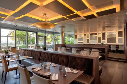 a restaurant with tables and chairs and a bar at Mövenpick Hotel Lausanne in Lausanne