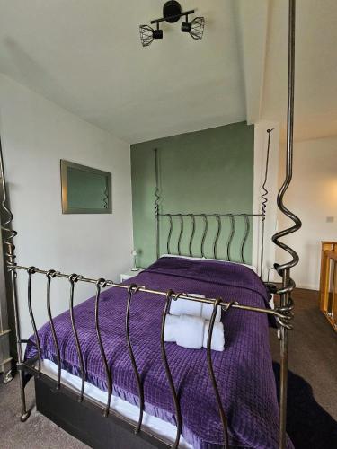 a bedroom with a bed with purple sheets and a fan at The Retreat at Plover Cottage Lindley in Huddersfield