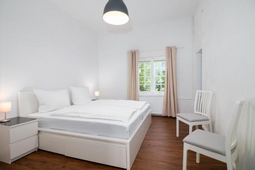 1 dormitorio blanco con 1 cama blanca y 1 silla en Schloss Glücksburg, en Glücksburg