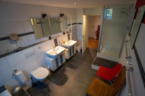 a bathroom with two sinks and a shower and a red chair at Jachthuus mit Anbau in Brilon