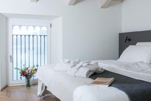 a white bedroom with a large bed and a window at Villa Rêverie - Boutique Hotel in Bellano
