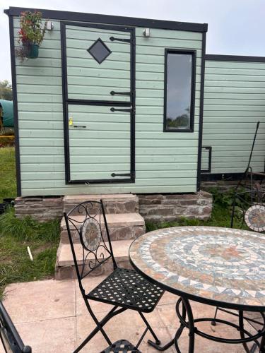 a patio with a table and chairs in front of a house at Bon yr Llew, Coity Bach in Brecon