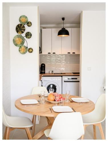 - une cuisine avec une table en bois et des chaises blanches dans l'établissement Charmant 2 pièces proche Disney & Paris avec jardin et Parking, à Collégien