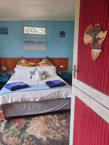a bedroom with a bed and a red door at Beach Cottage Pumula in Pumula