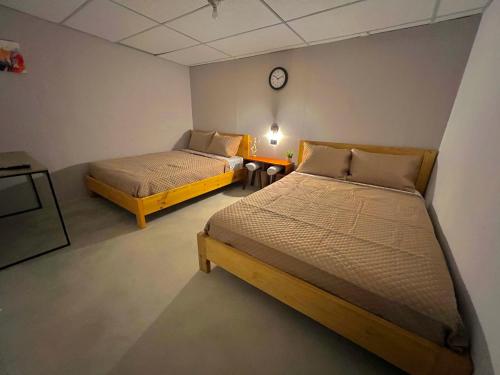 two beds in a room with a clock on the wall at Hotel Citadin Zona 4 in Guatemala