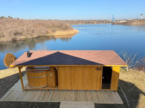 a wooden dog house with two trash cans next to a lake at LifeHarbour Limanu in Limanu