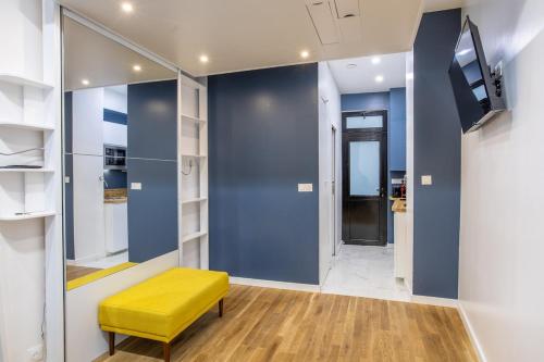 une chambre avec un banc jaune et un mur avec des étagères dans l'établissement Cosy studio 2 - Grenelle Eiffel Tower, à Paris