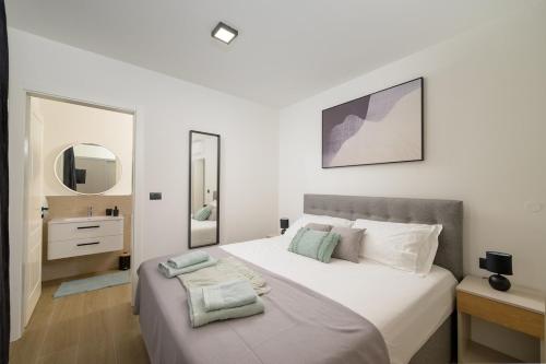 a white bedroom with a large bed and a mirror at Villa Brajde by IstriaLux in Gajana