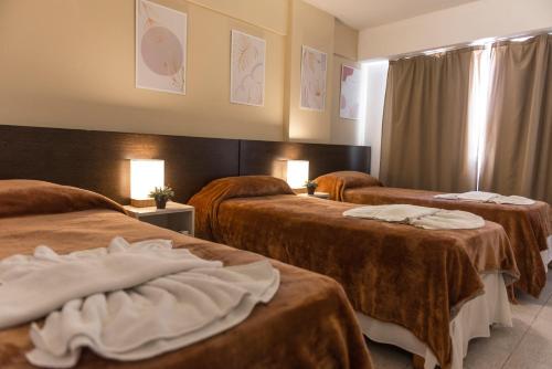 a hotel room with three beds with brown blankets at Novum Suites in Córdoba