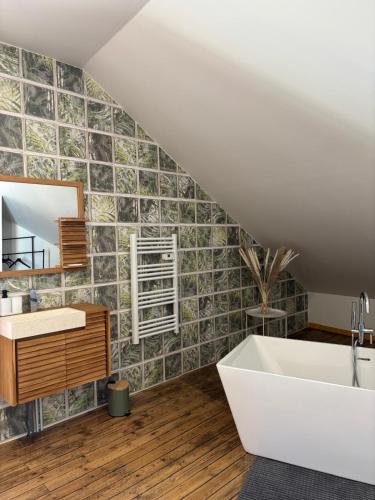 La salle de bains est pourvue d'une baignoire blanche et d'un mur en carrelage. dans l'établissement Superbe Loft Spa Jacuzzi Cinema, à Néris-les-Bains