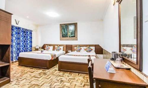 a hotel room with two beds and a table and a desk at Kevins Bearshola Residency in Kodaikānāl