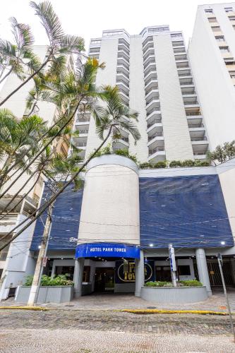 a large building with palm trees in front of it at Park Tower Campinas Residence by Nacional Inn in Campinas
