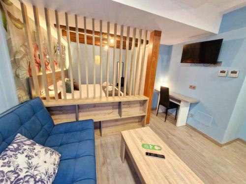 a living room with a blue couch and a desk at Feeling Home - Suites&Rooms in León