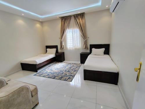 a room with two beds and a couch and a window at شذا المصيف لبيوت العطلات in Al Shafa